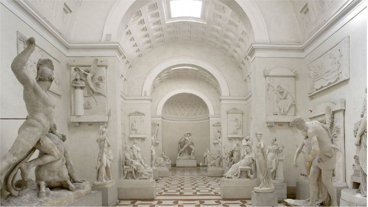 Neoclassical sculpture hall in a museum with classical marble statues and vaulted skylit ceiling