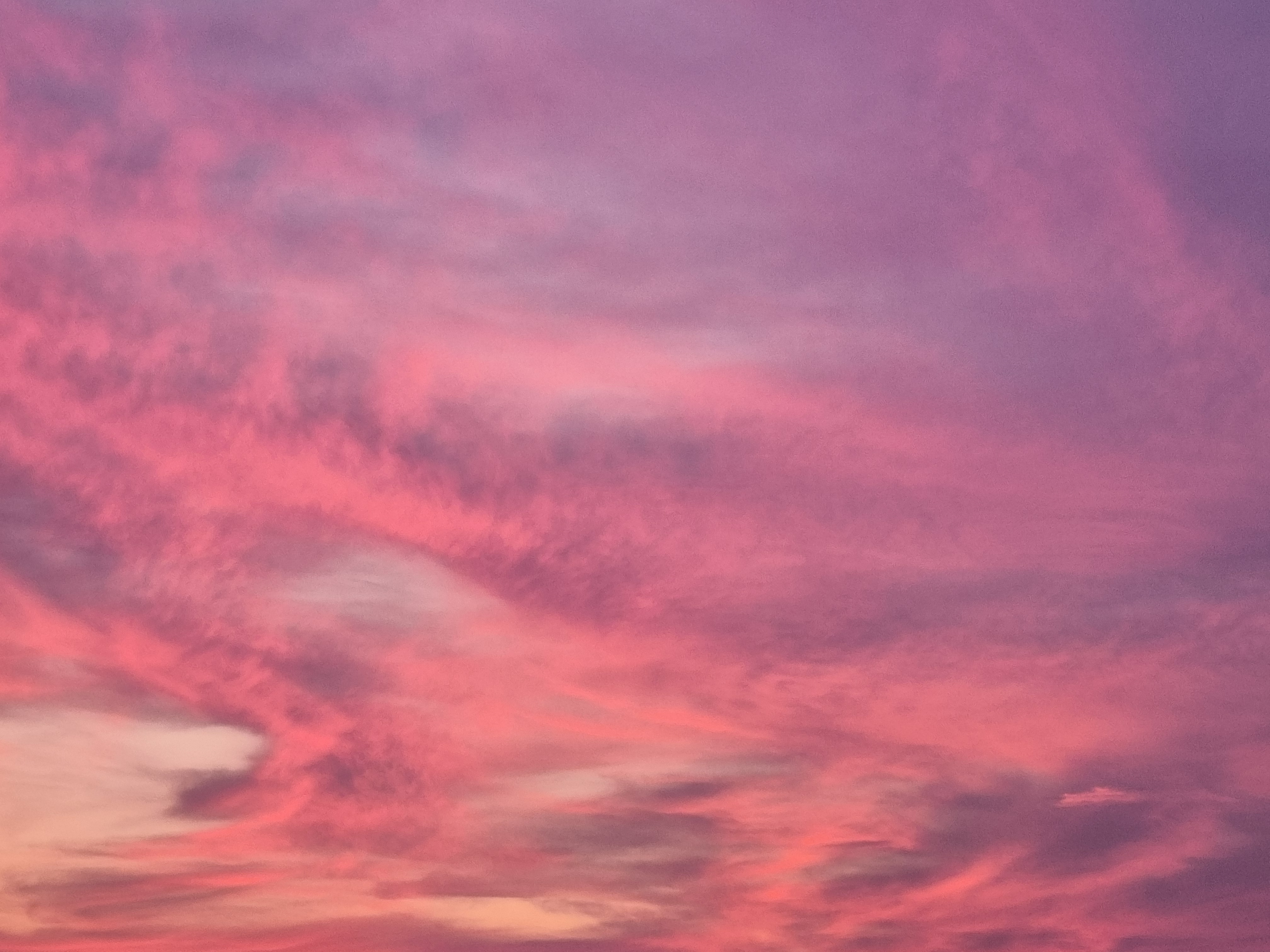 Dramatic sunset sky filled with vivid pink, magenta, and peach clouds at dusk