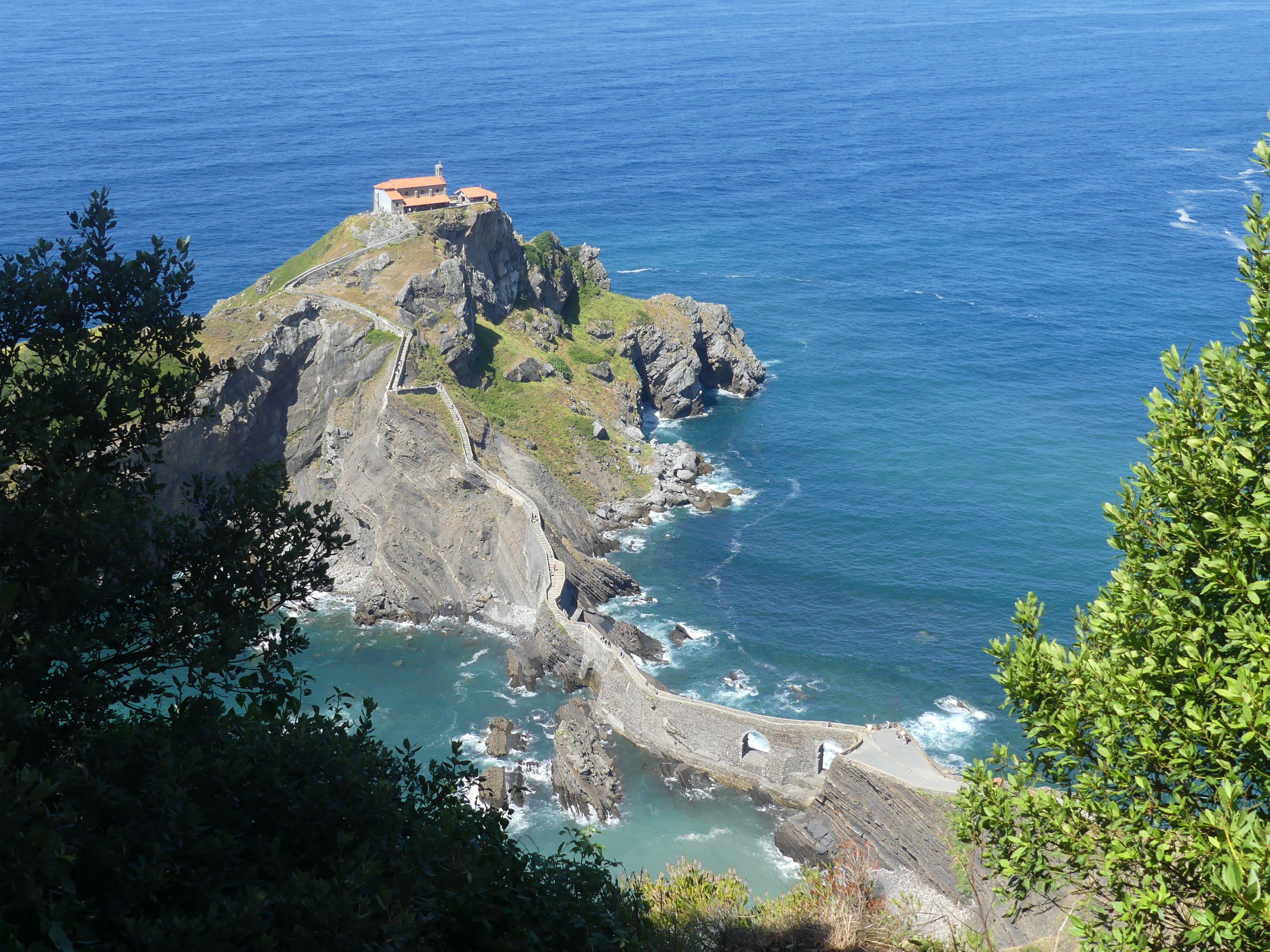 Coastal view of San Juan de Gaztelugatxe island church and winding stone bridge surrounded by blue sea